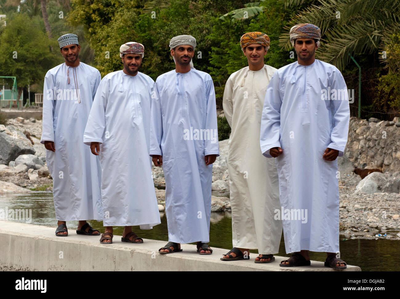 Five young Omani men wearings traditional dishdasha festive clothes during a trip to the hot springs of Ain A'Thawwarah, Nakhl Stock Photo