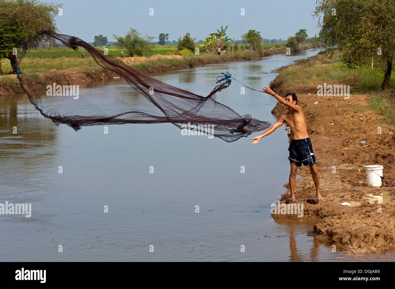 Fisherman fishing by casting a throw net in a river, Battambang
