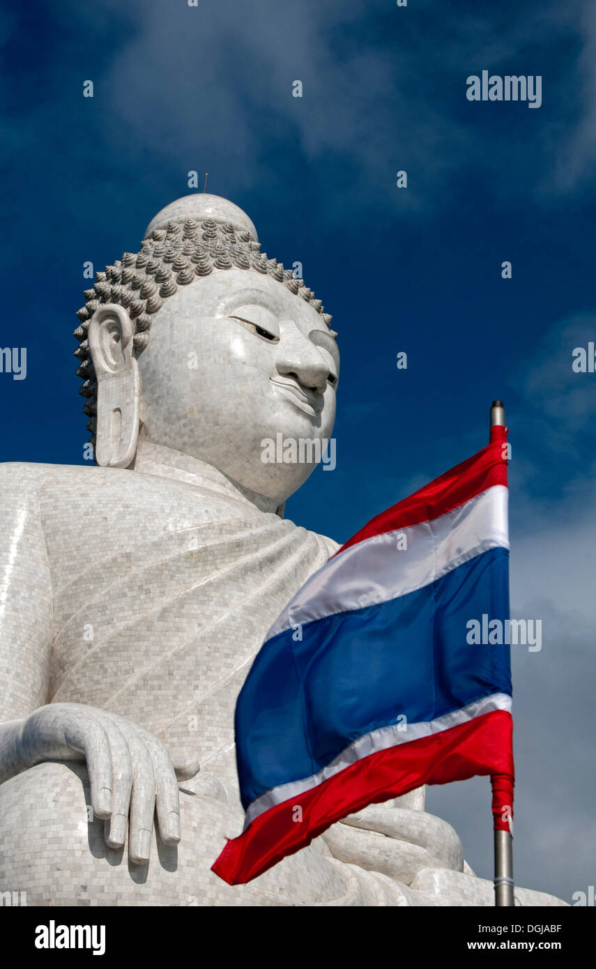 Great Buddha made of Burmese alabaster seated in a Maravichai pose with the national flag of Thailand, Chalong, Phuket Province Stock Photo