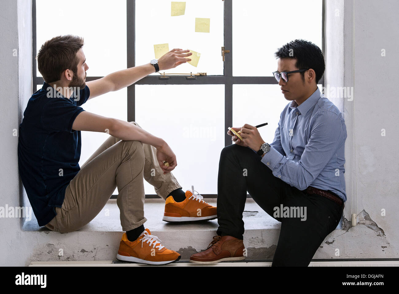 Two young male designers sharing ideas on post it notes Stock Photo