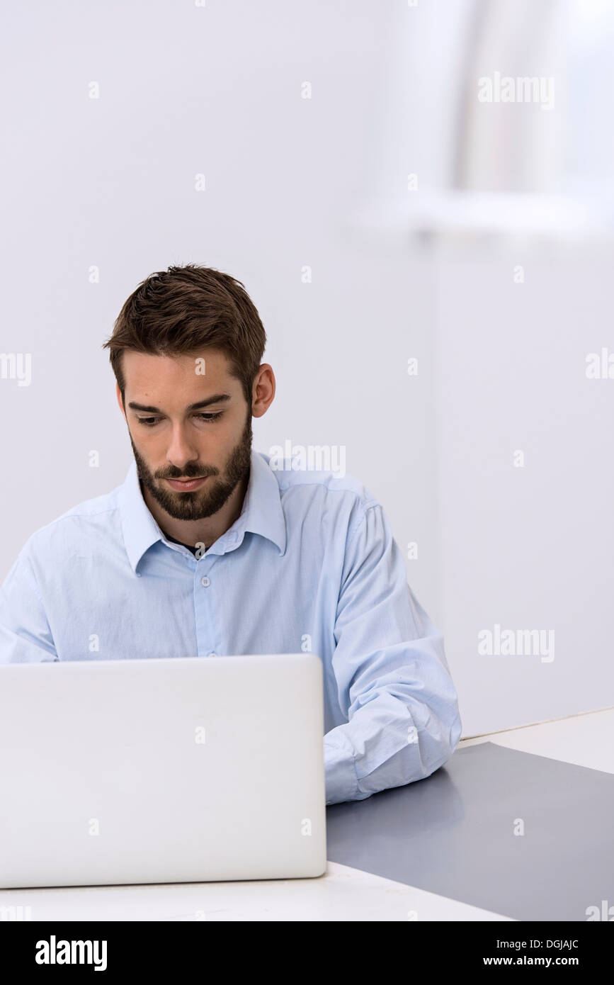 Young man sitting behind laptop in office Stock Photo