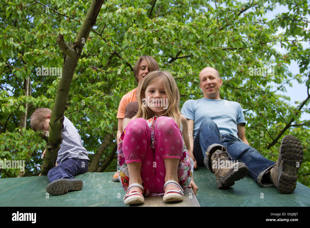 Family with two children sitting on playhouse roof Stock Photo