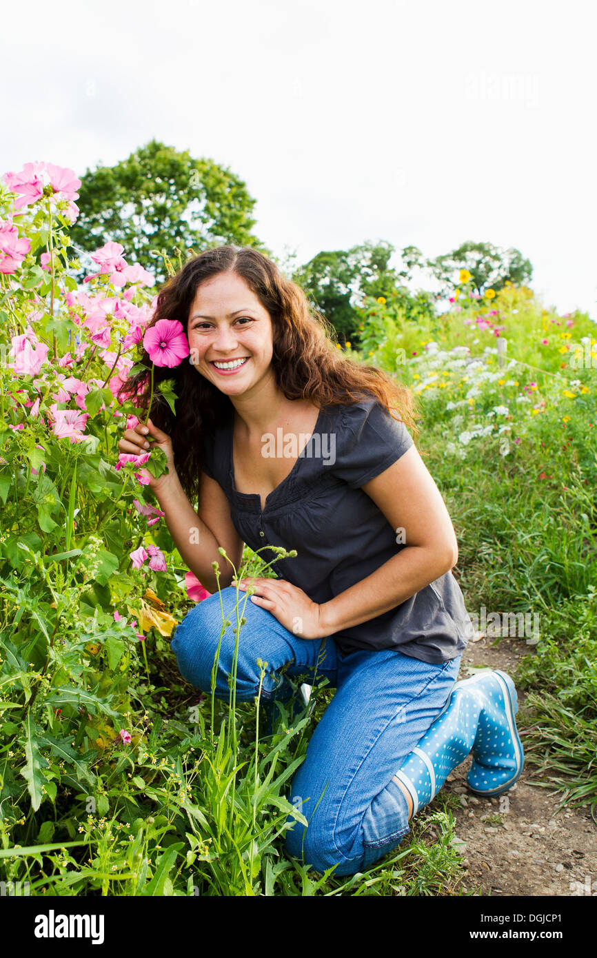 Portrait of young woman holding pink flower in allotment Stock Photo