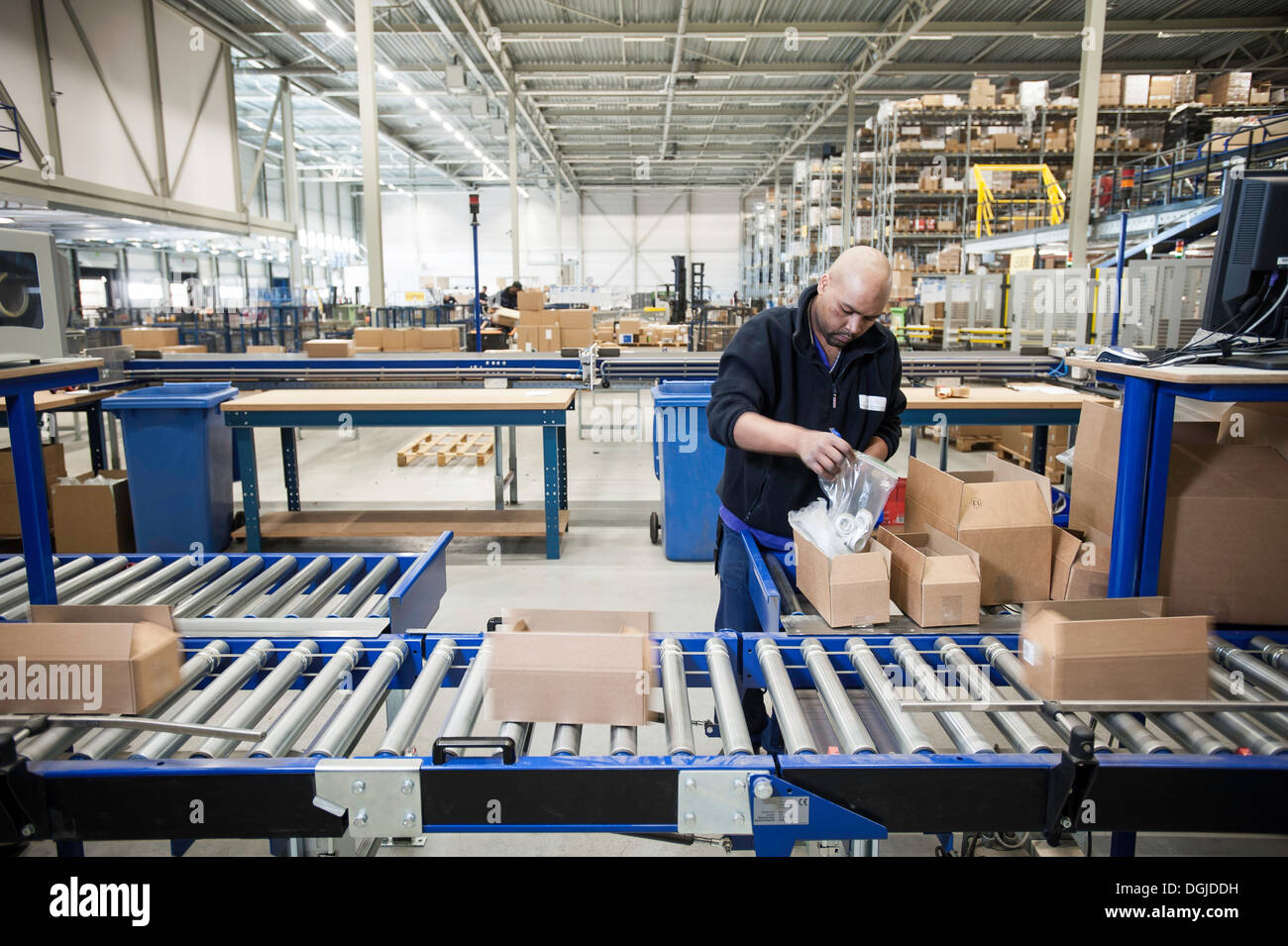 Male warehouse worker packing cardboard boxes for conveyer belt Stock Photo