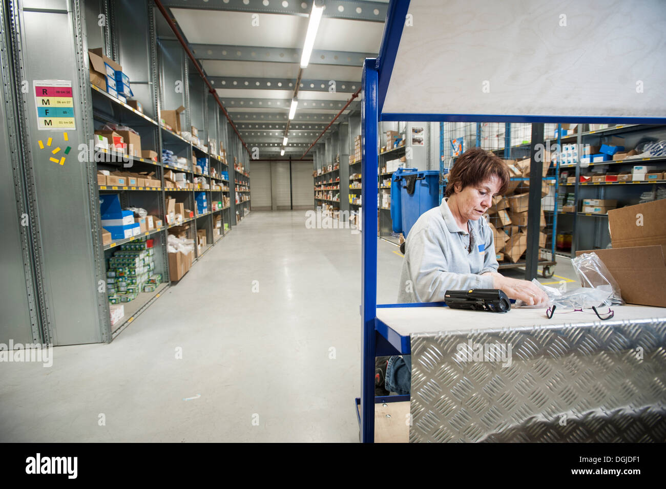 Female warehouse worker preparing orders on delivery trolley Stock Photo