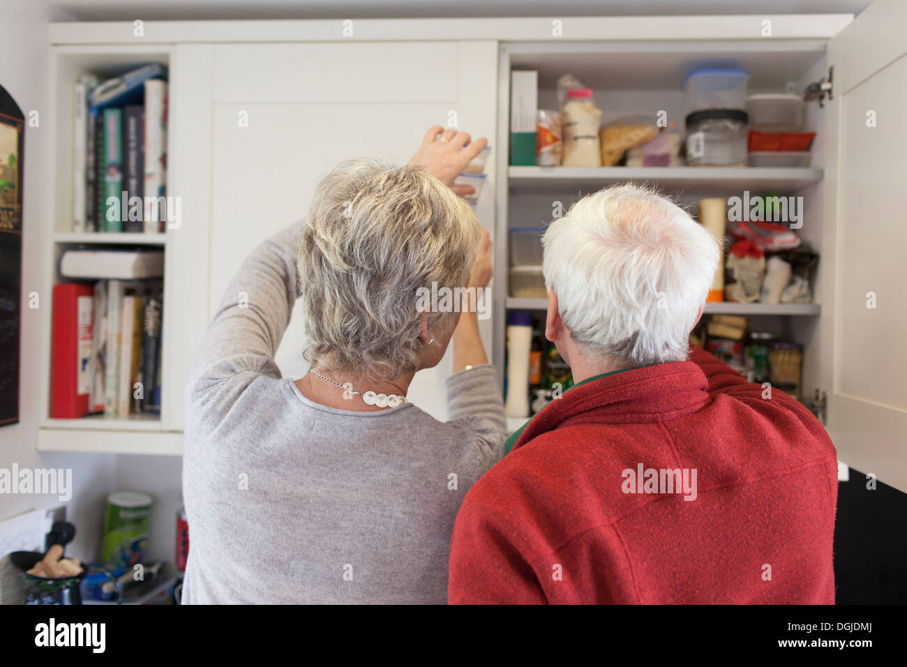 Senior couple checking kitchen cupboards Stock Photo