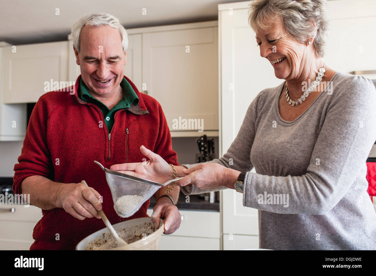 Senior couple sieving flour into mixing bowl Stock Photo