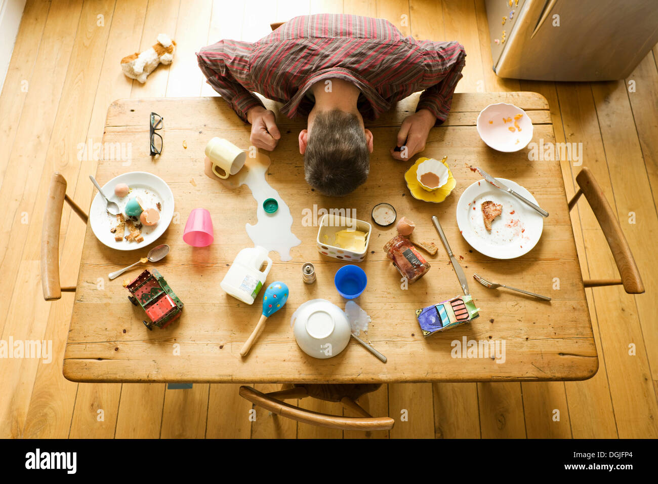 Overhead view of breakfast table with mature man amongst messy plates Stock Photo