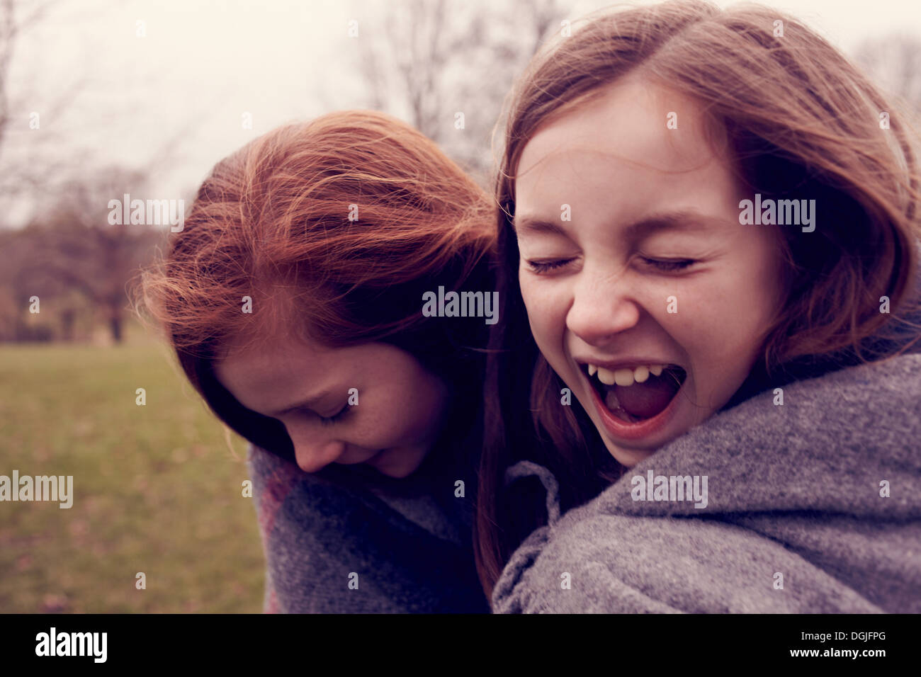 Young friends wrapped in a blanket and laughing outdoors Stock Photo