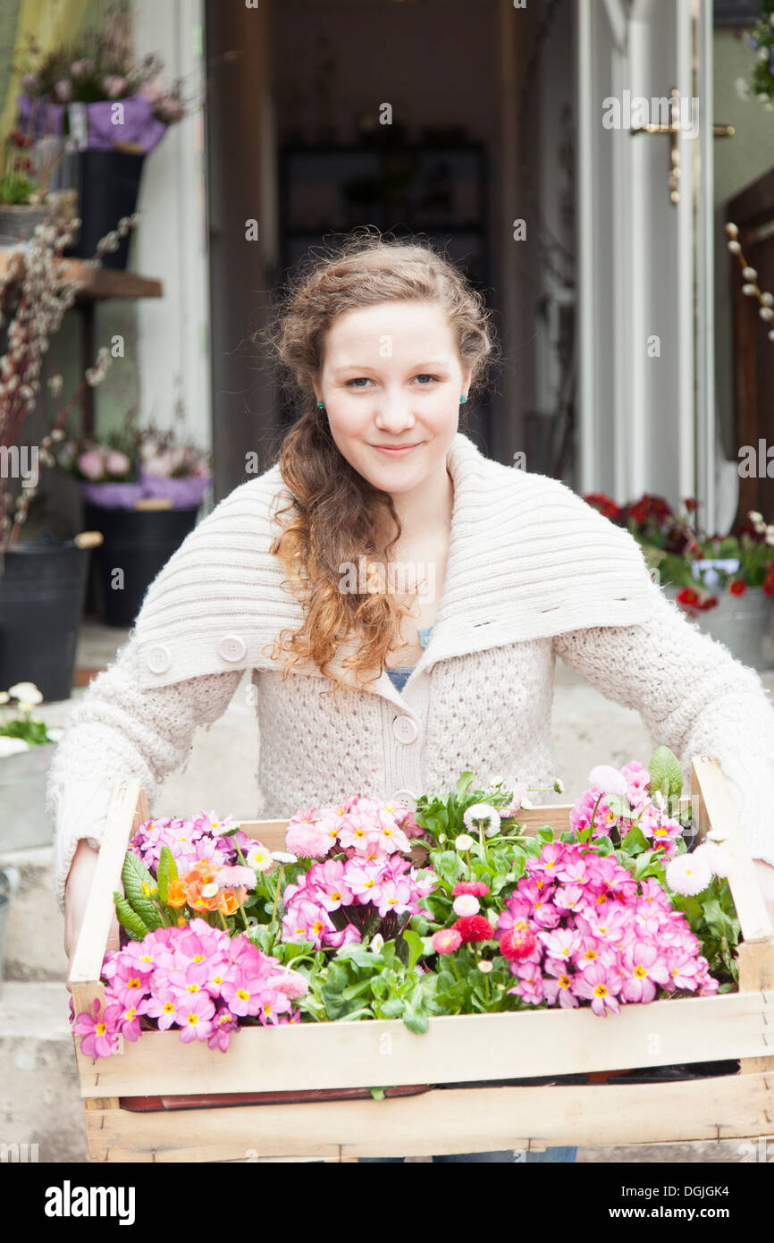 Portrait of teenage girl carrying crate of flowers Stock Photo