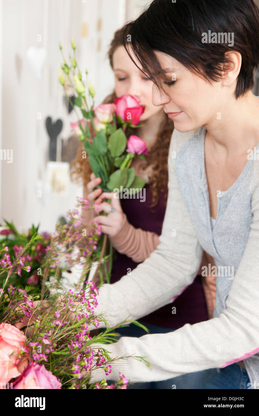 Mid adult woman and teenage girl choosing flowers in florists Stock Photo
