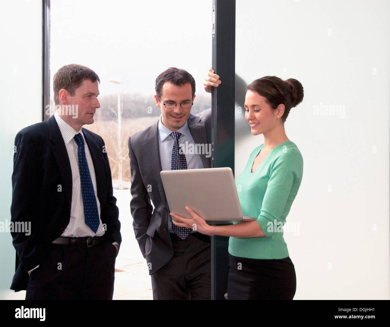 Three colleagues talking, woman holding laptop Stock Photo