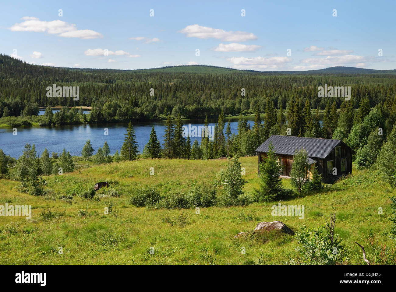 Wood house near the blue lake in the taiga forest Stock Photo