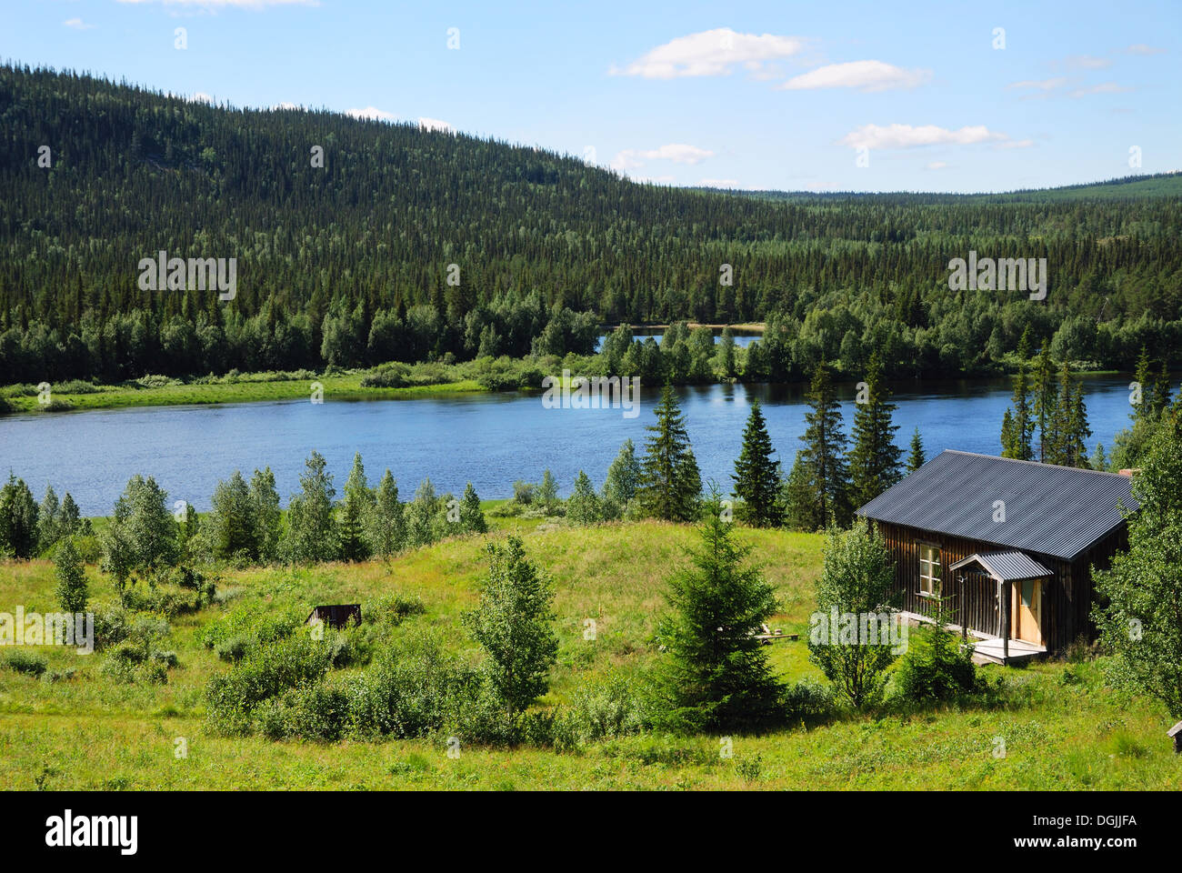 Wood house near the blue lake in the middle of taiga forest Stock Photo