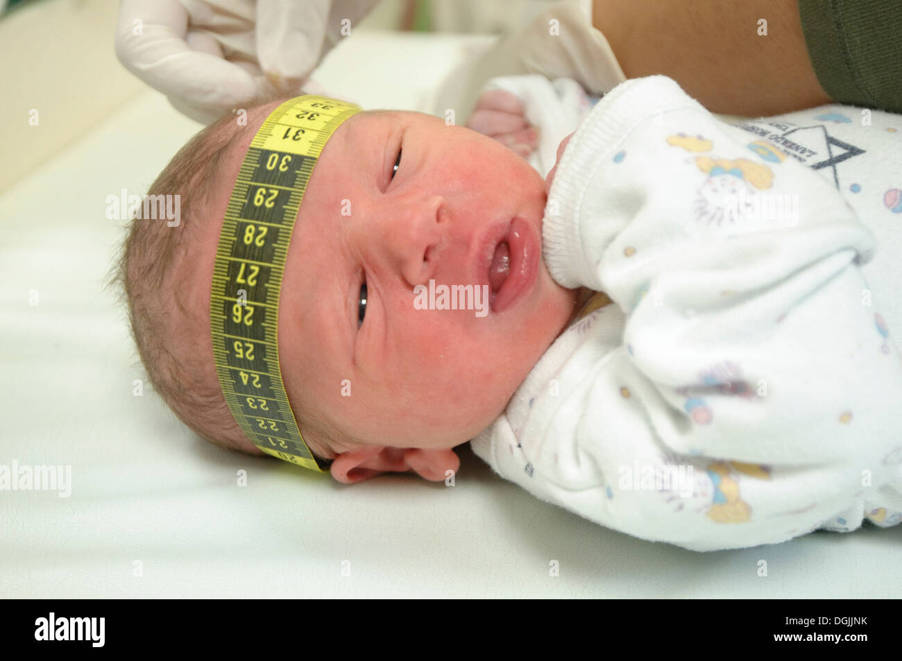 The head of a one day old baby boy is being measured with a tape measure - model release available Stock Photo