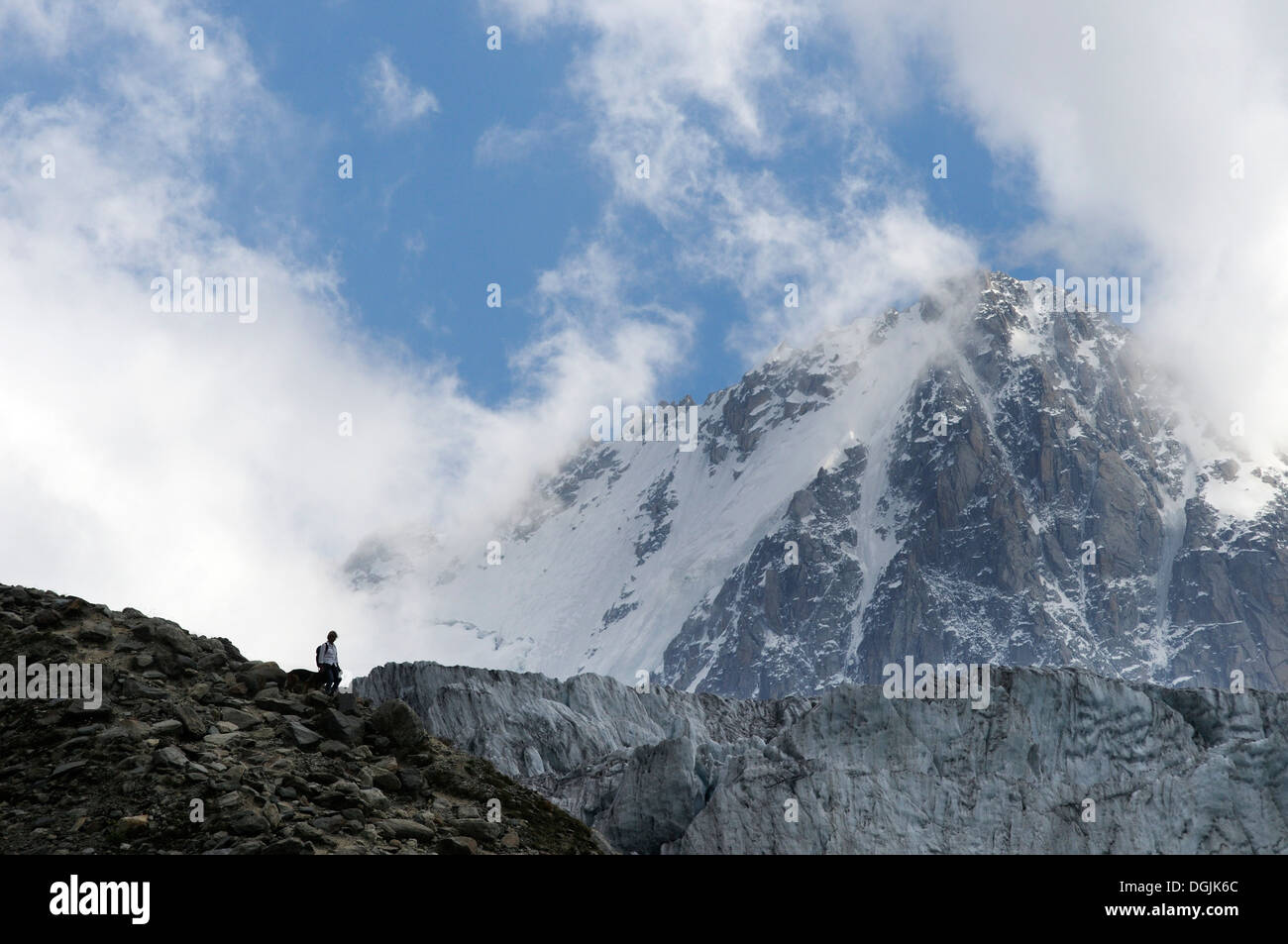 A walker descending  a path in the french alps with the Aiguille de Chardonnet behind Stock Photo