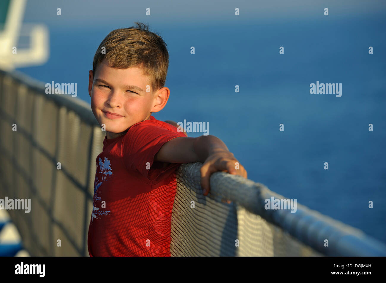 Boy, 8, leaning against a ship's railing Stock Photo