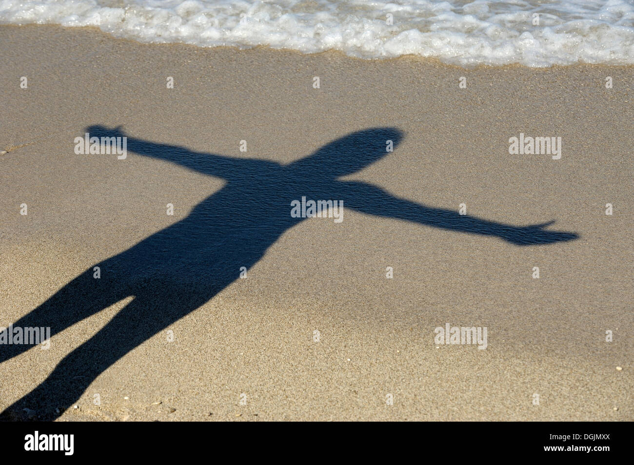 Woman with outstretched arms casting her shadow on the beach, Kathisma, Lefkas or Lefkada, Greece, Europe Stock Photo