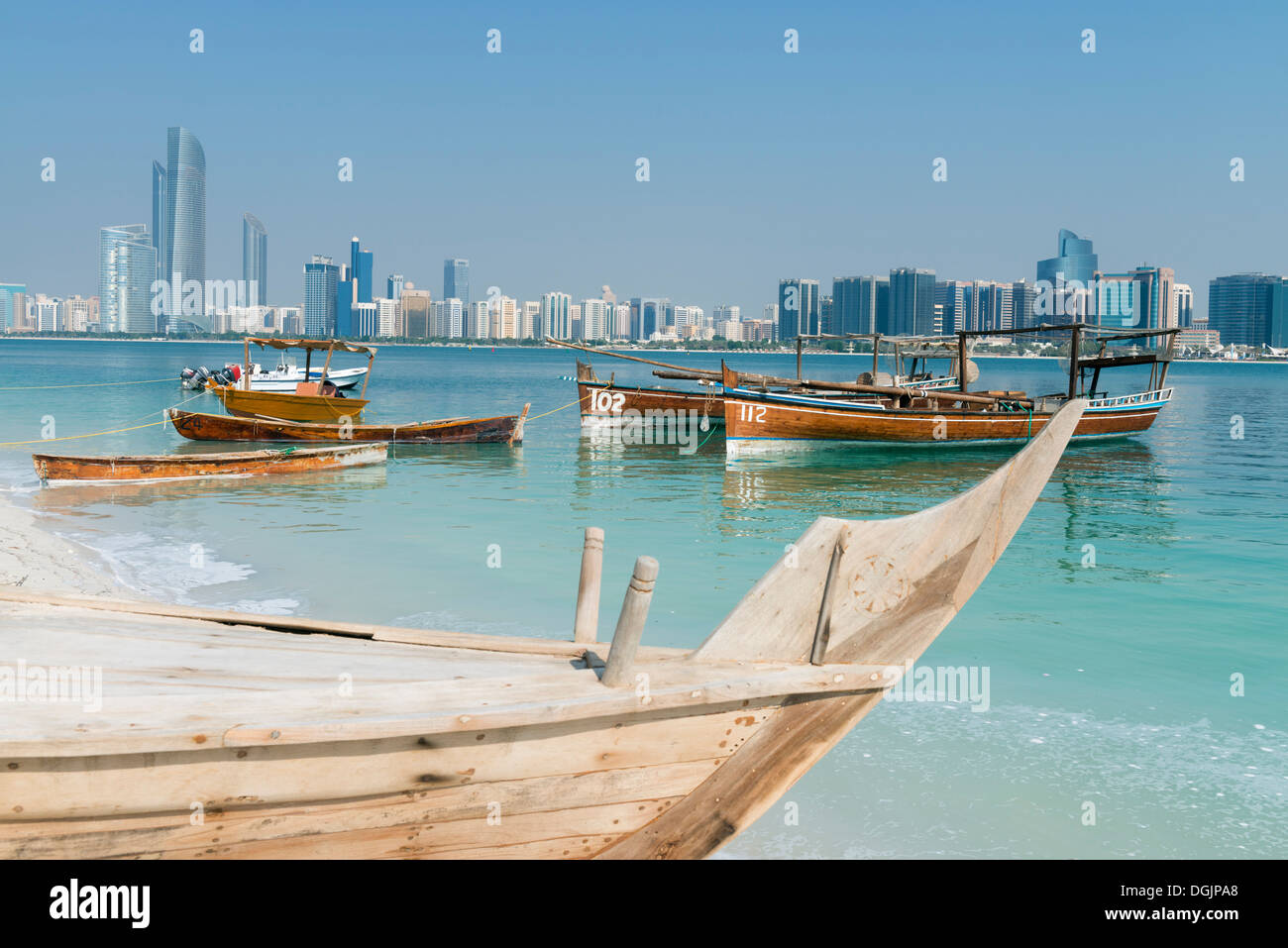 Skyline of modern Abu Dhabi and old traditional fishing boats in Heritage Village in Abu Dhabi in United Arab Emirates UAE Stock Photo