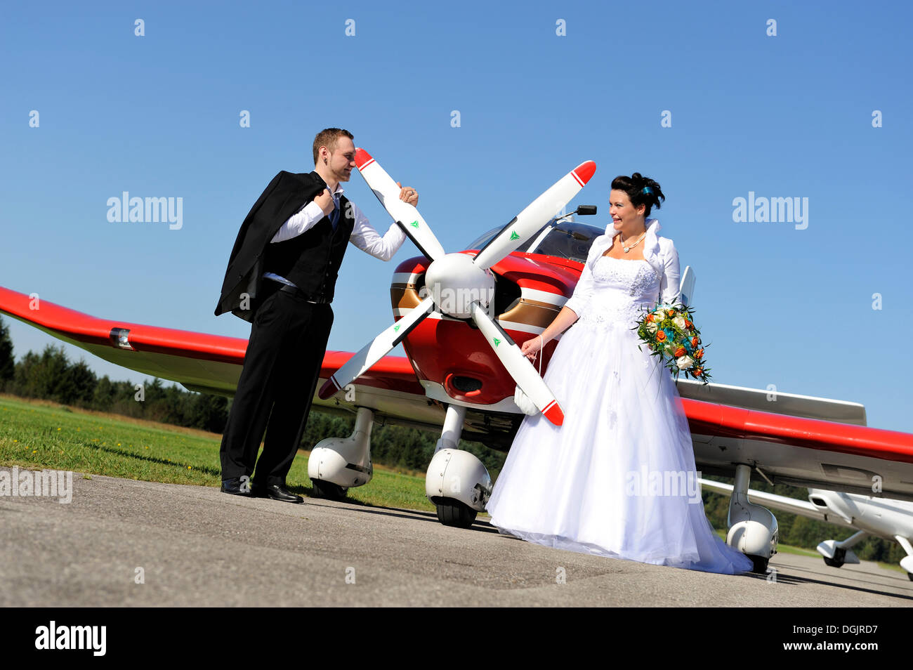 Young bridal couple posing in front of a propeller plane Stock Photo