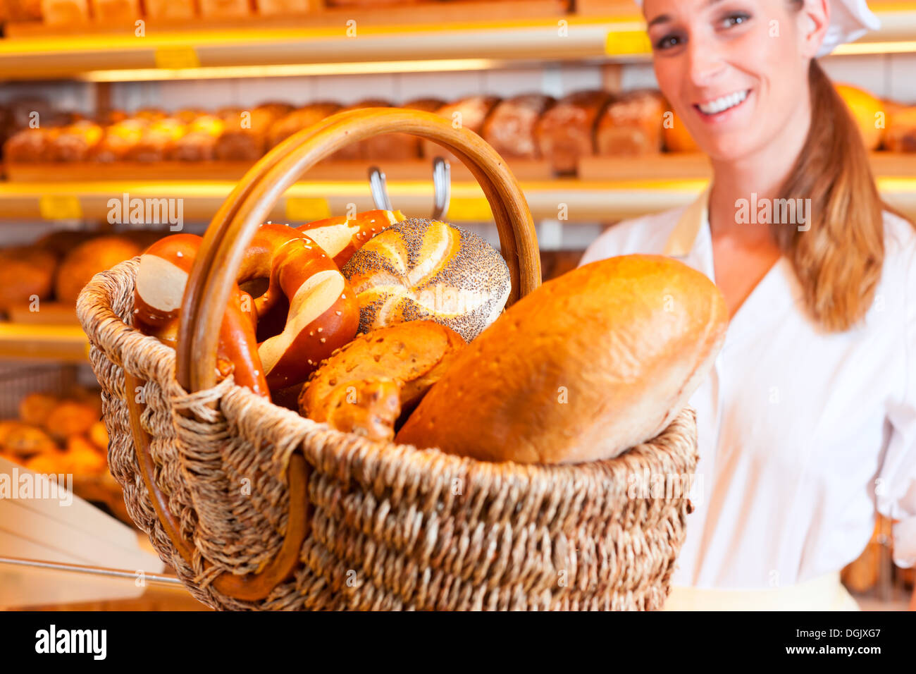 Female baker or saleswoman in her bakery with fresh pastries and bakery