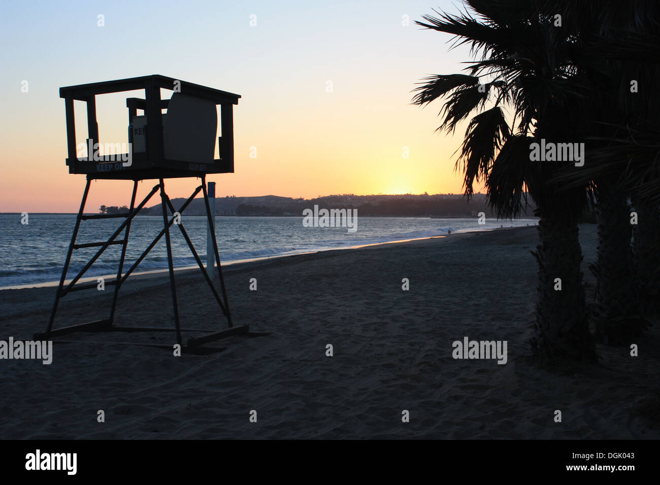 Sun setting over Dana Point beach with palm tree and lifeguard tower in Southern California Stock Photo