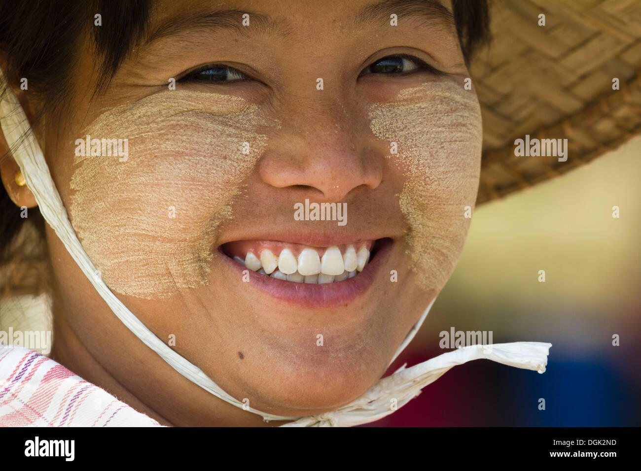 A smiling girl with Thanaka makeup and wearing conical straw hat in Mingun in Myanmar. Stock Photo