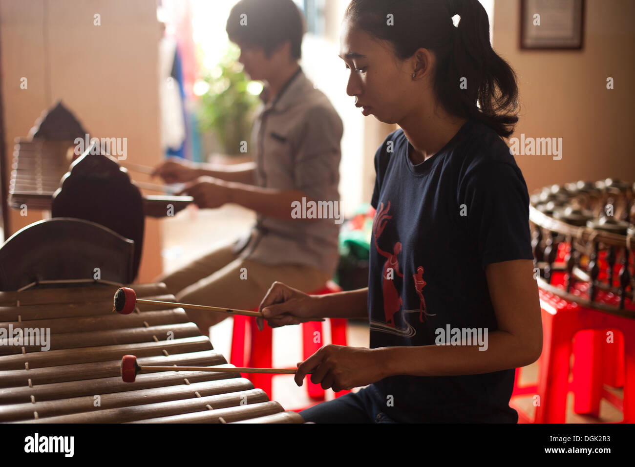 A young woman practices playing a traditional Cambodian xylophone in