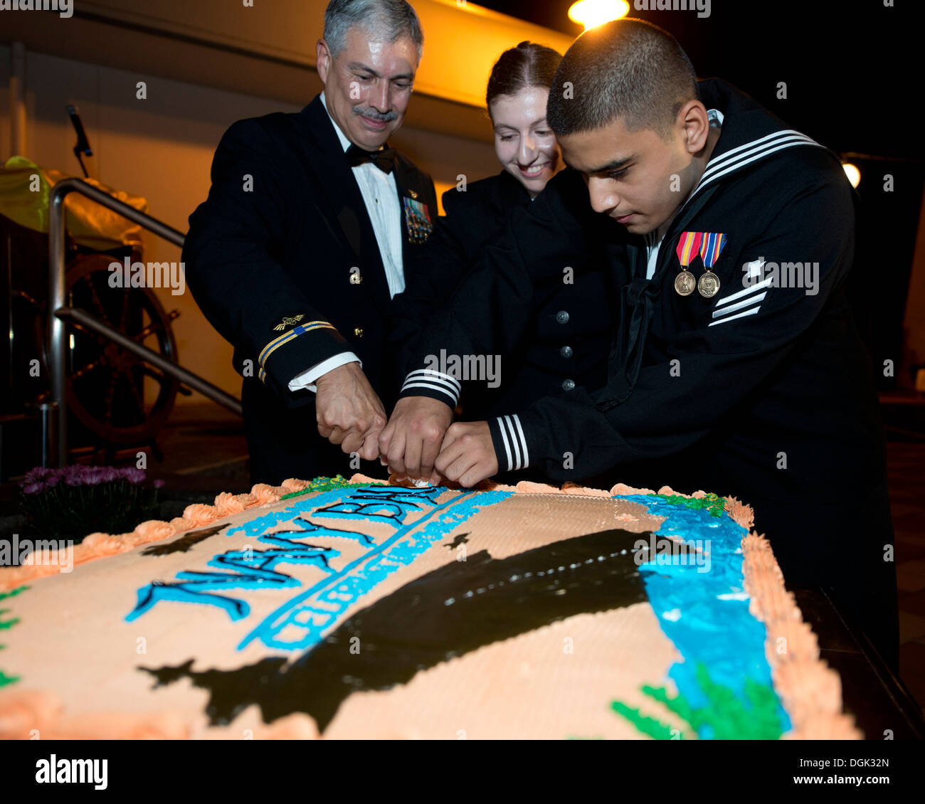 Commander, Fleet Air Forward Officer in Charge Chief Warrant Officer 5 Luis Quiroga cuts the cake with Personnel Specialist Seaman Apprentice Sarah Garson (Center) and Personnel Specialist Seaman Jamal Etrata, both from Naval Air Facility (NAF) Atsugi's P Stock Photo