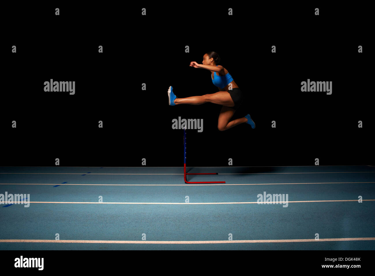Young female athlete jumping hurdle Stock Photo