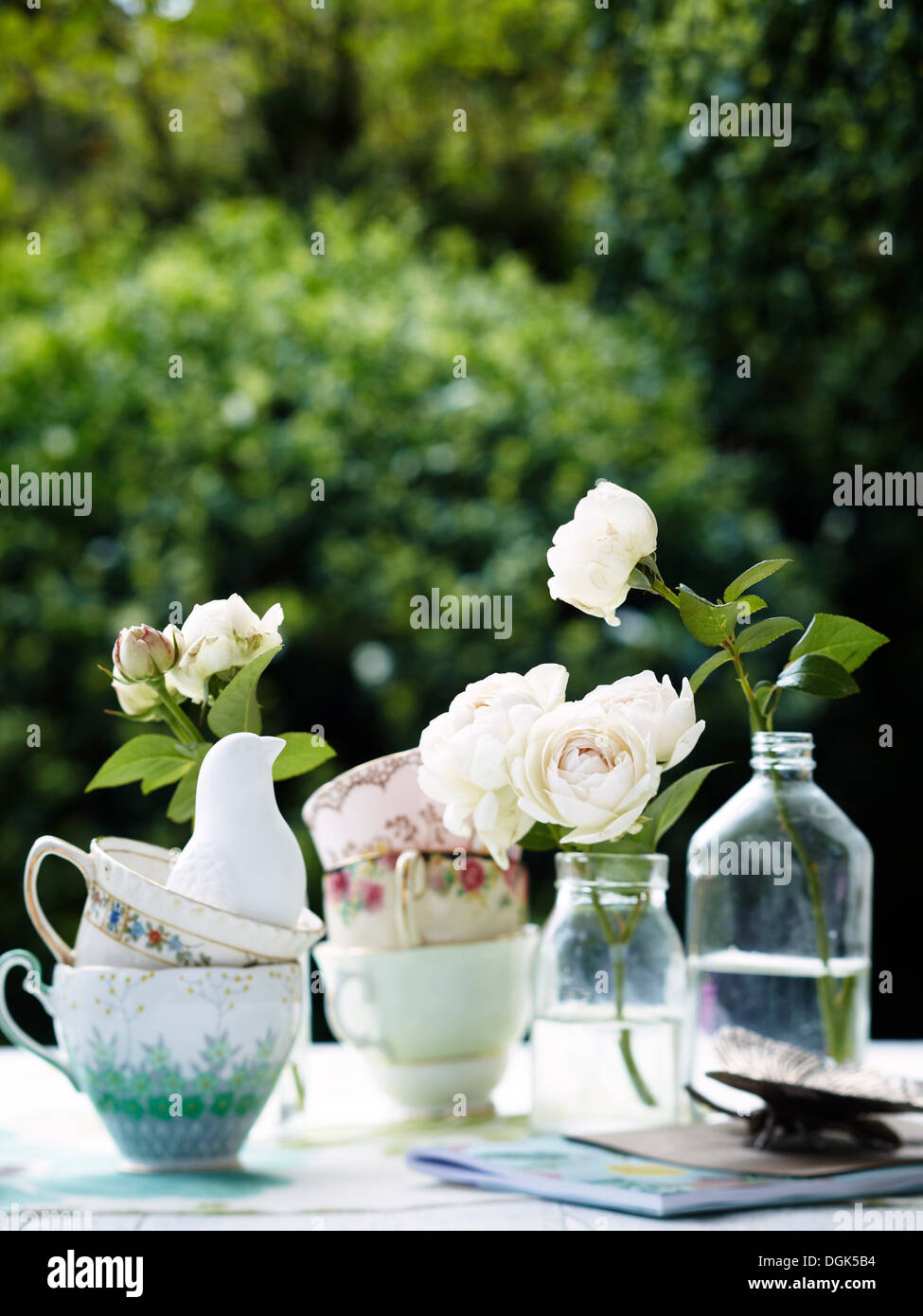 Flowers in vintage bottles with teacups Stock Photo