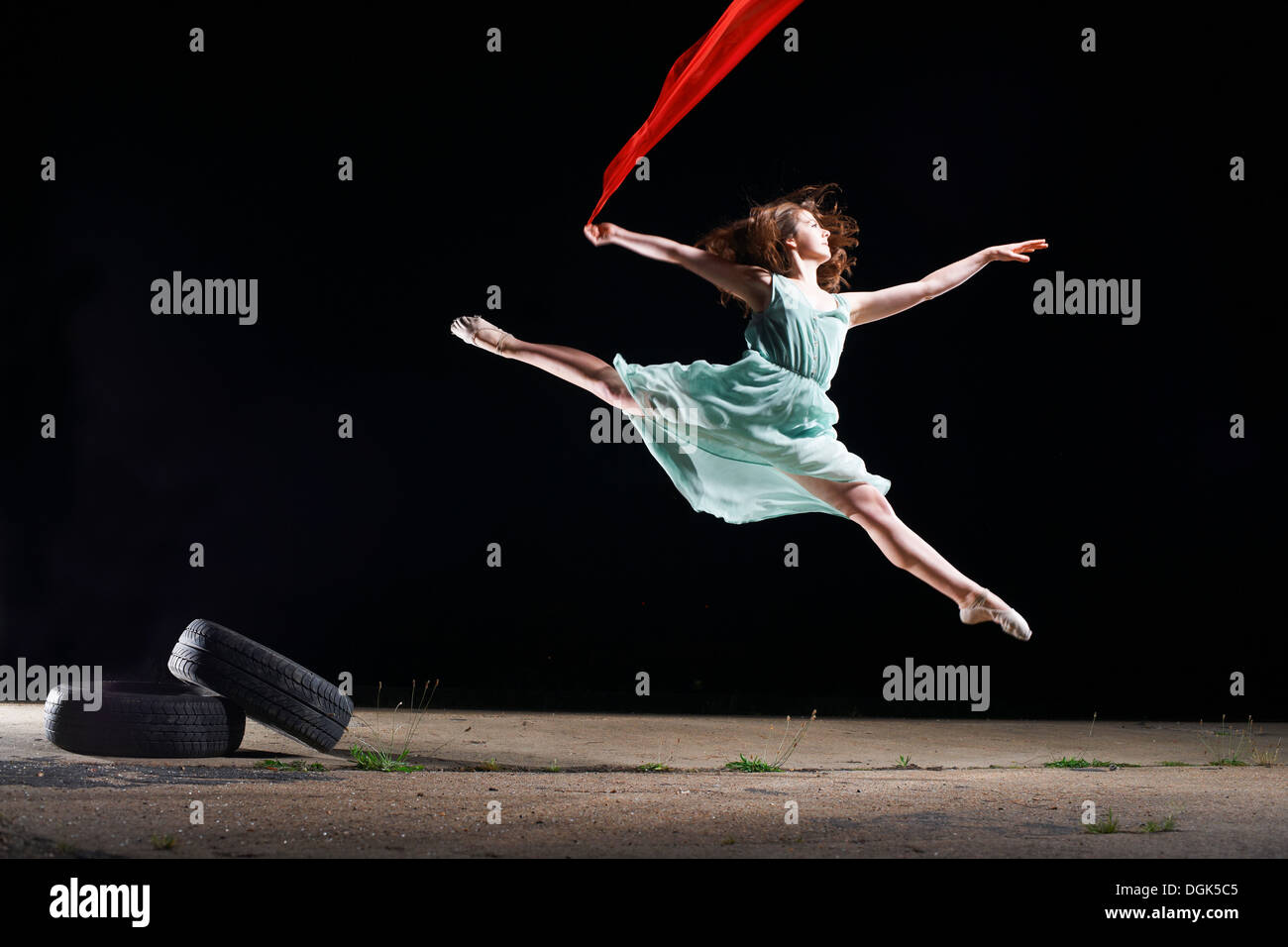 Ballet dancer leaping mid air holding red scarf Stock Photo
