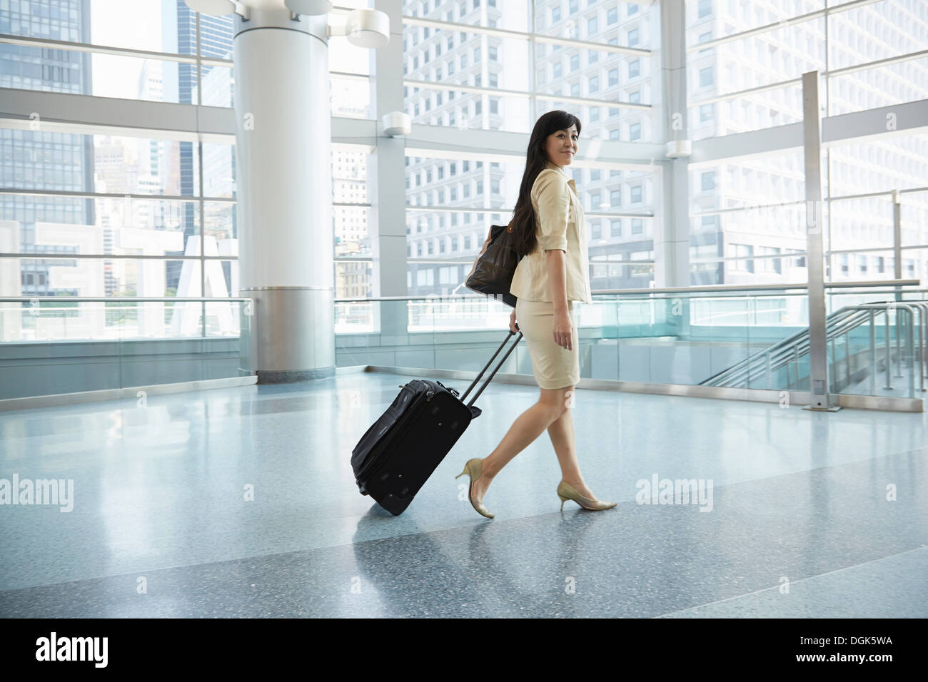 Businesswoman pulling wheeled suitcase through Staten Island Ferry terminal Stock Photo