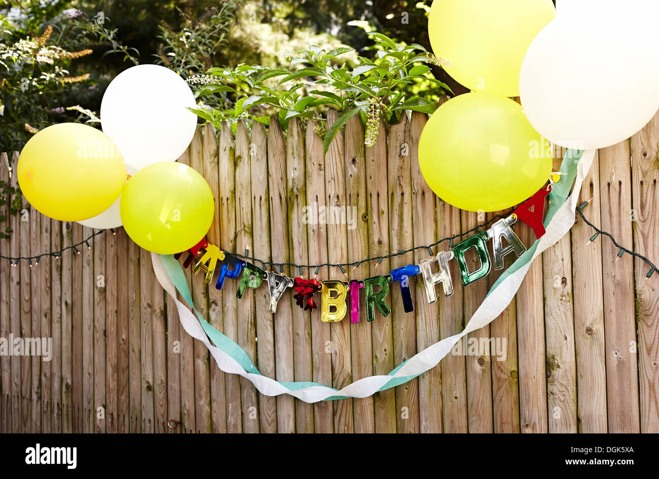 Happy Birthday banner and balloons tied to fence Stock Photo