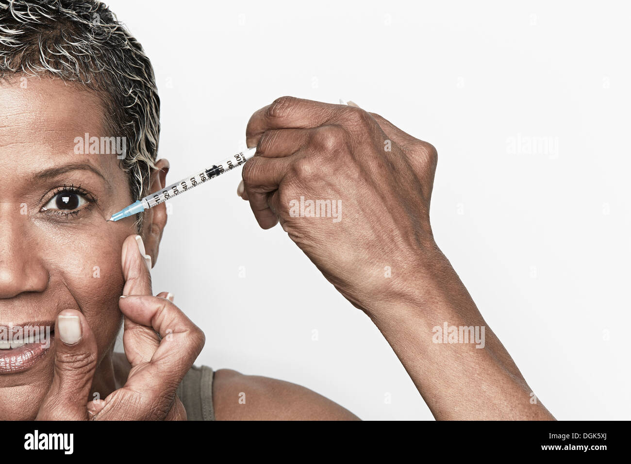 Senior woman injecting herself with botox Stock Photo