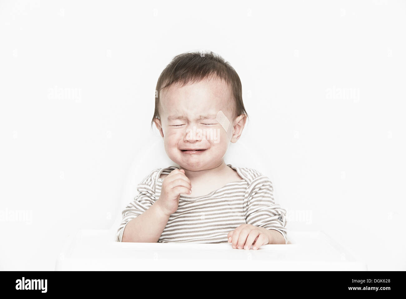 Baby boy with adhesive plaster on face, crying Stock Photo