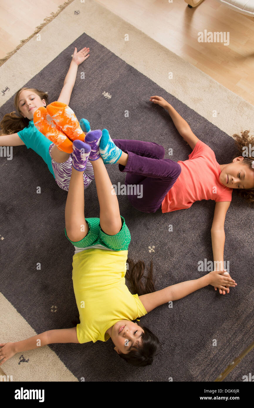 Three girls lying on floor with legs raised Stock Photo - Alamy