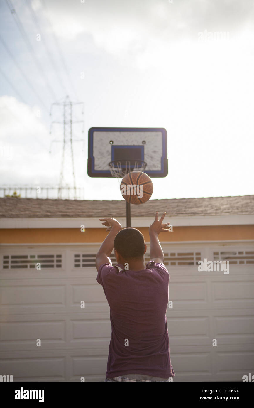 Boy throwing basketball towards hoop Stock Photo Alamy
