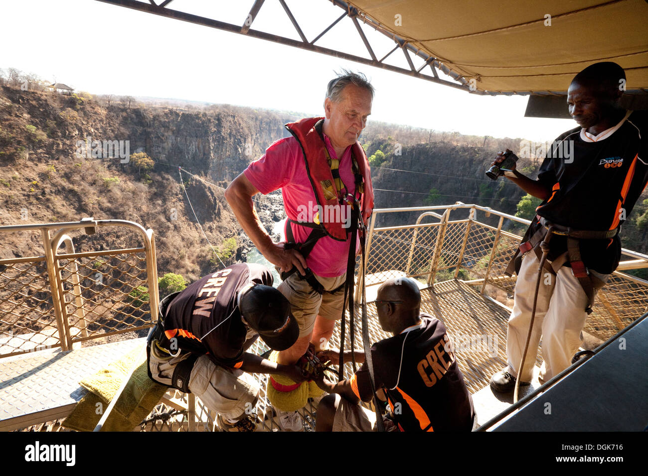An elderly retired caucasian man age 70s years old preparing to bungee jump, Victoria Falls Bridge, Zambia, Africa Stock Photo