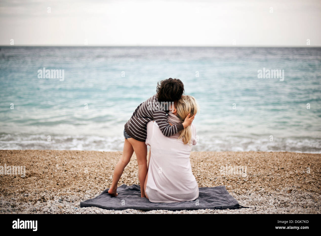 Boy hugging mother on a beach, rear view Stock Photo