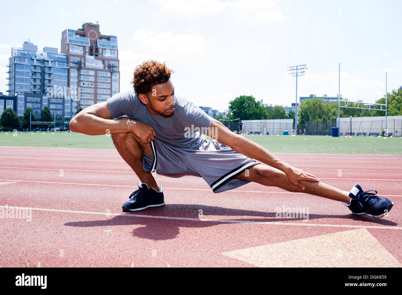 Young man stretching leg on running track Stock Photo - Alamy