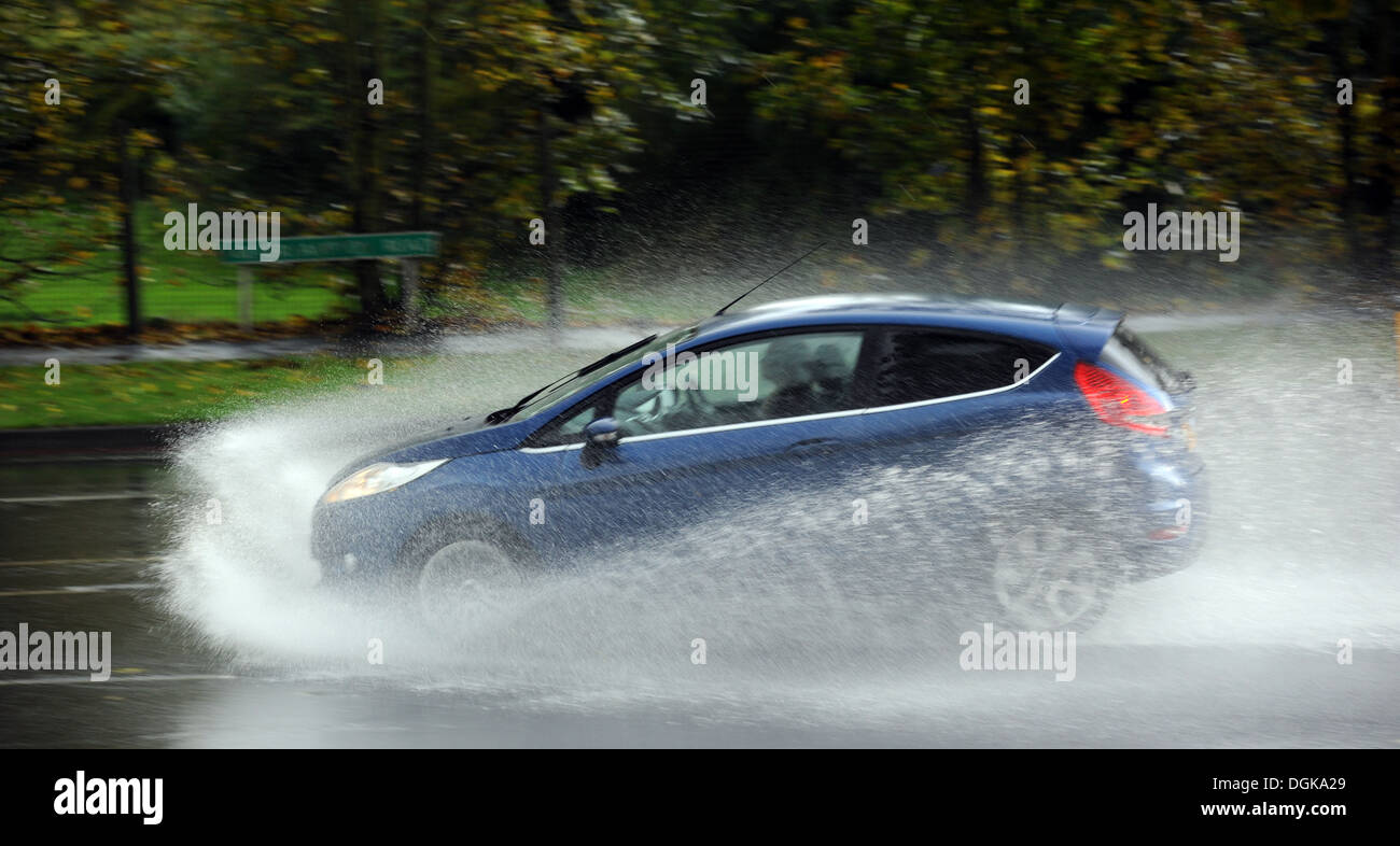 A CAR TRAVELLING THROUGH HEAVY RAIN WATER SPRAY ON A PUBLIC ROAD RE WEATHER STANDING WET SKID SKIDDING WINTER MOTORISTS UK Stock Photo