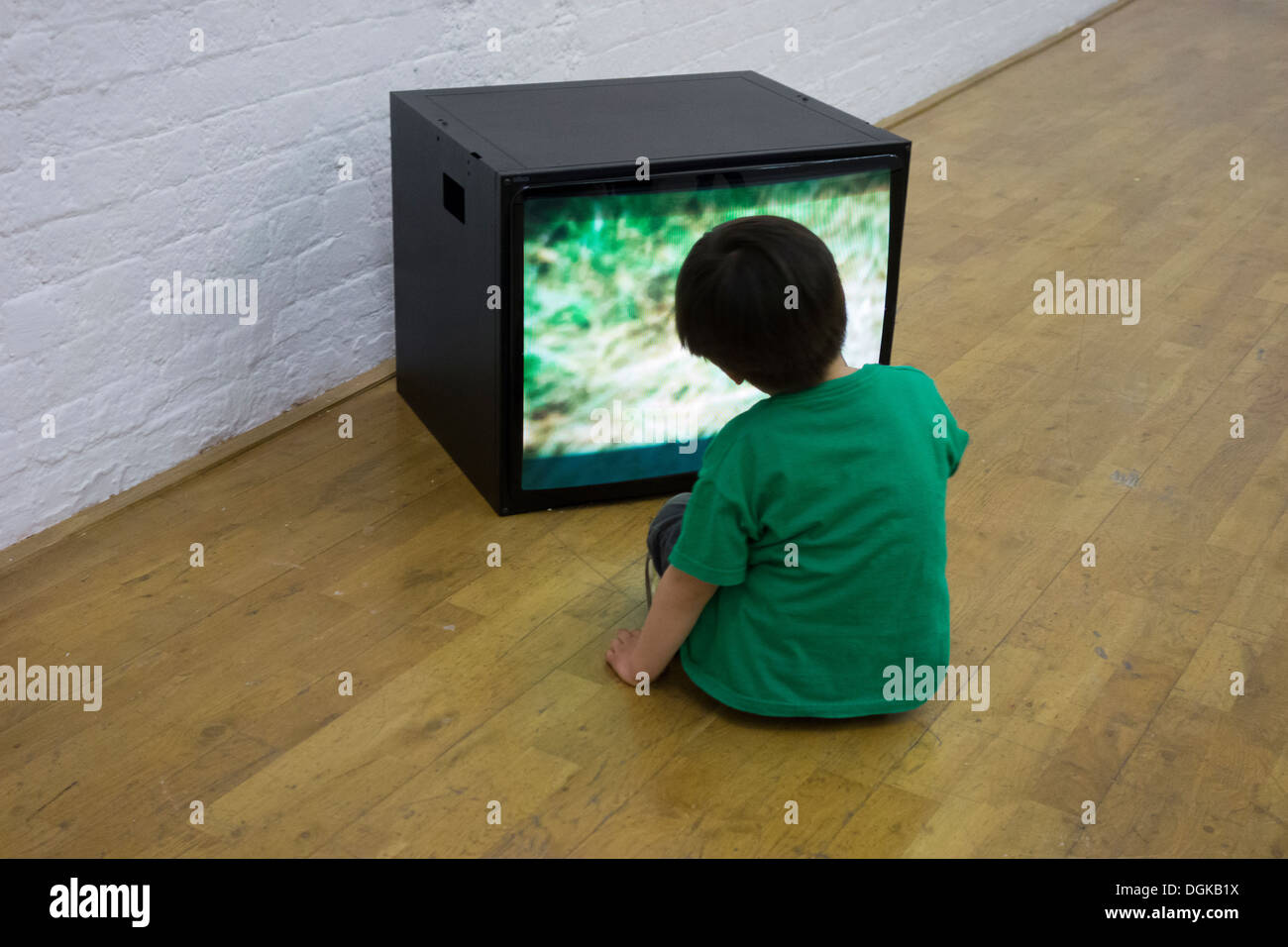 A small child hypnotised by TV in an installation at the Oxford Modern Art Gallery. Stock Photo