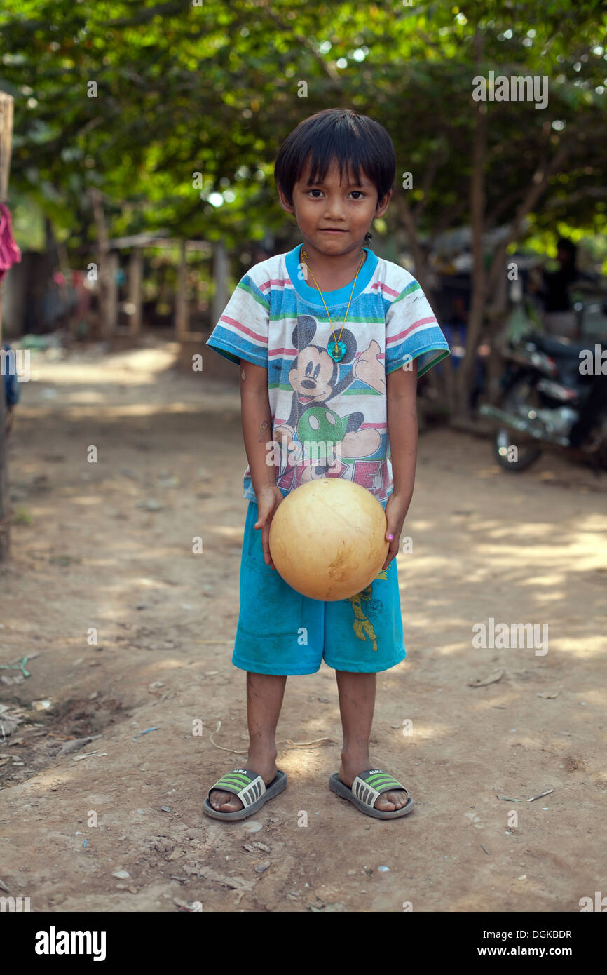 Portrait of a young boy with a ball in a small village outside of Phnom Penh, Cambodia. Photos © Dennis Drenner 2013. Stock Photo