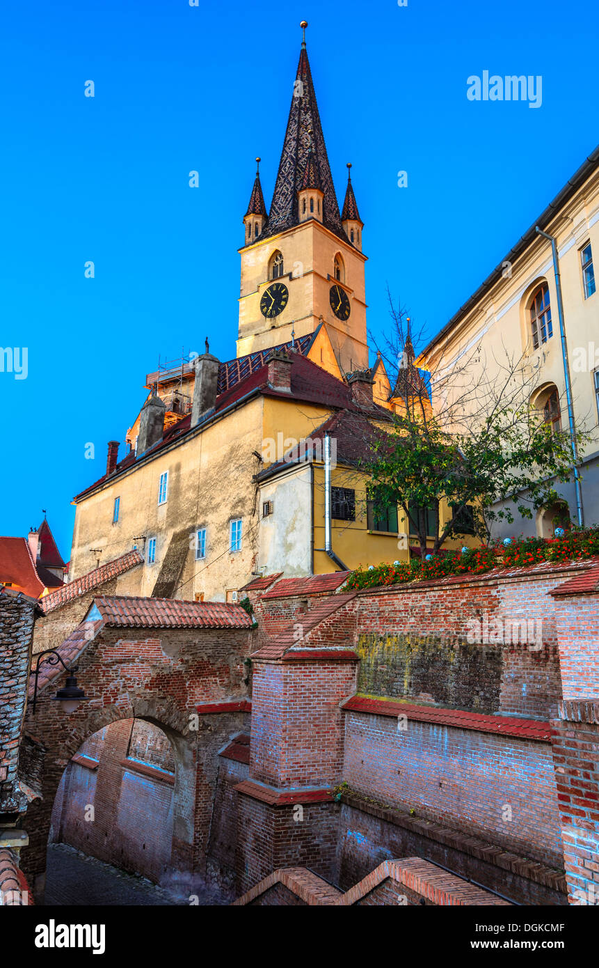 Evanghelical Church's famous tower, landmark of Sibiu, with a medieval street and some of the old town fortification walls Stock Photo