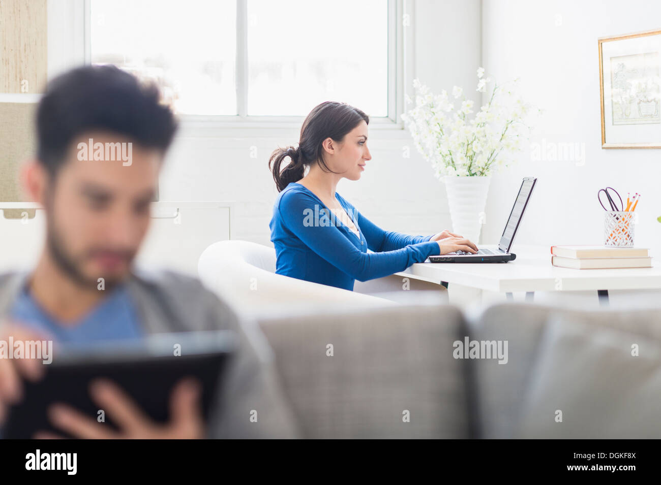 Woman using laptop and man using digital tablet at home Stock Photo