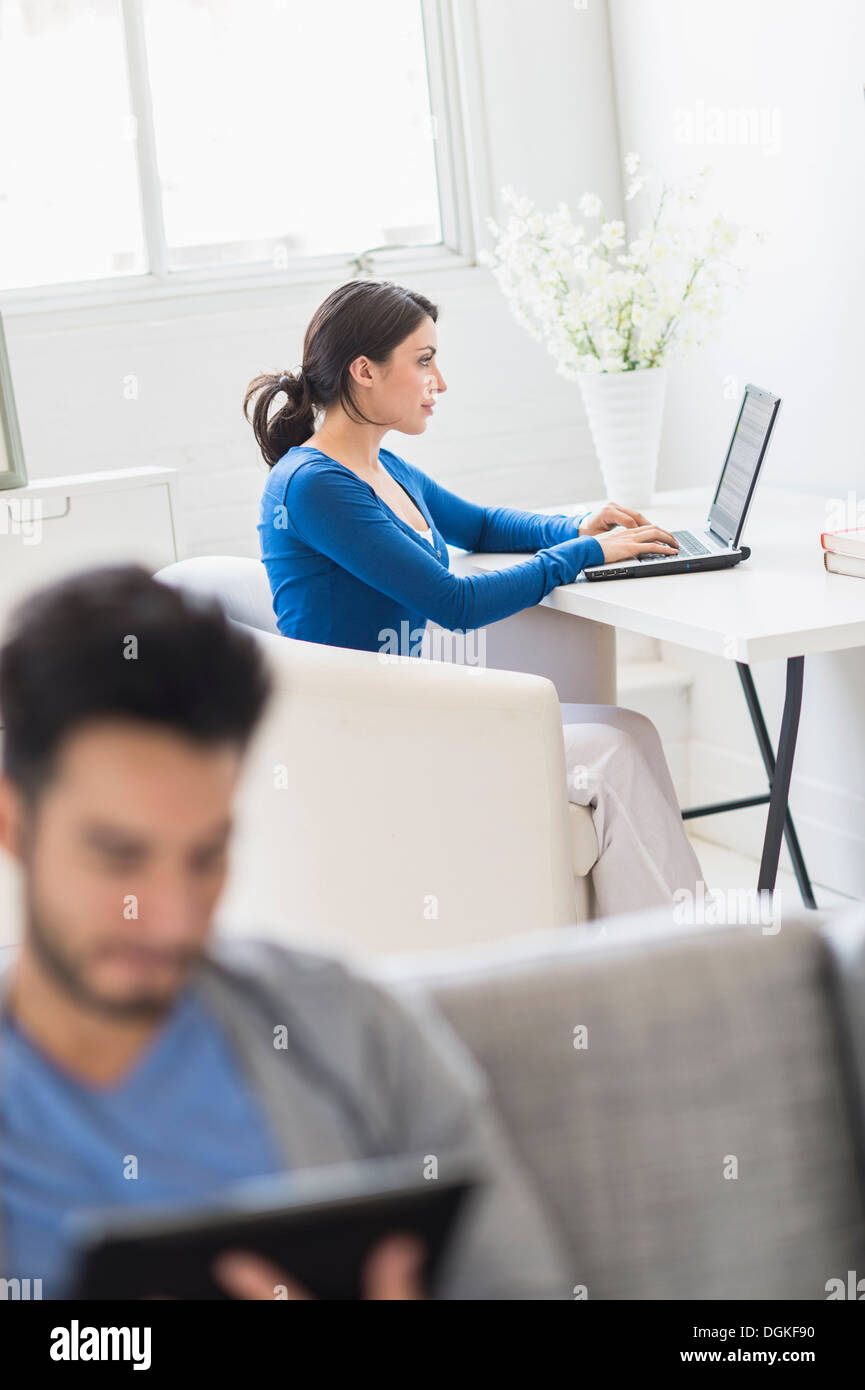 Woman using laptop and man using digital tablet at home Stock Photo