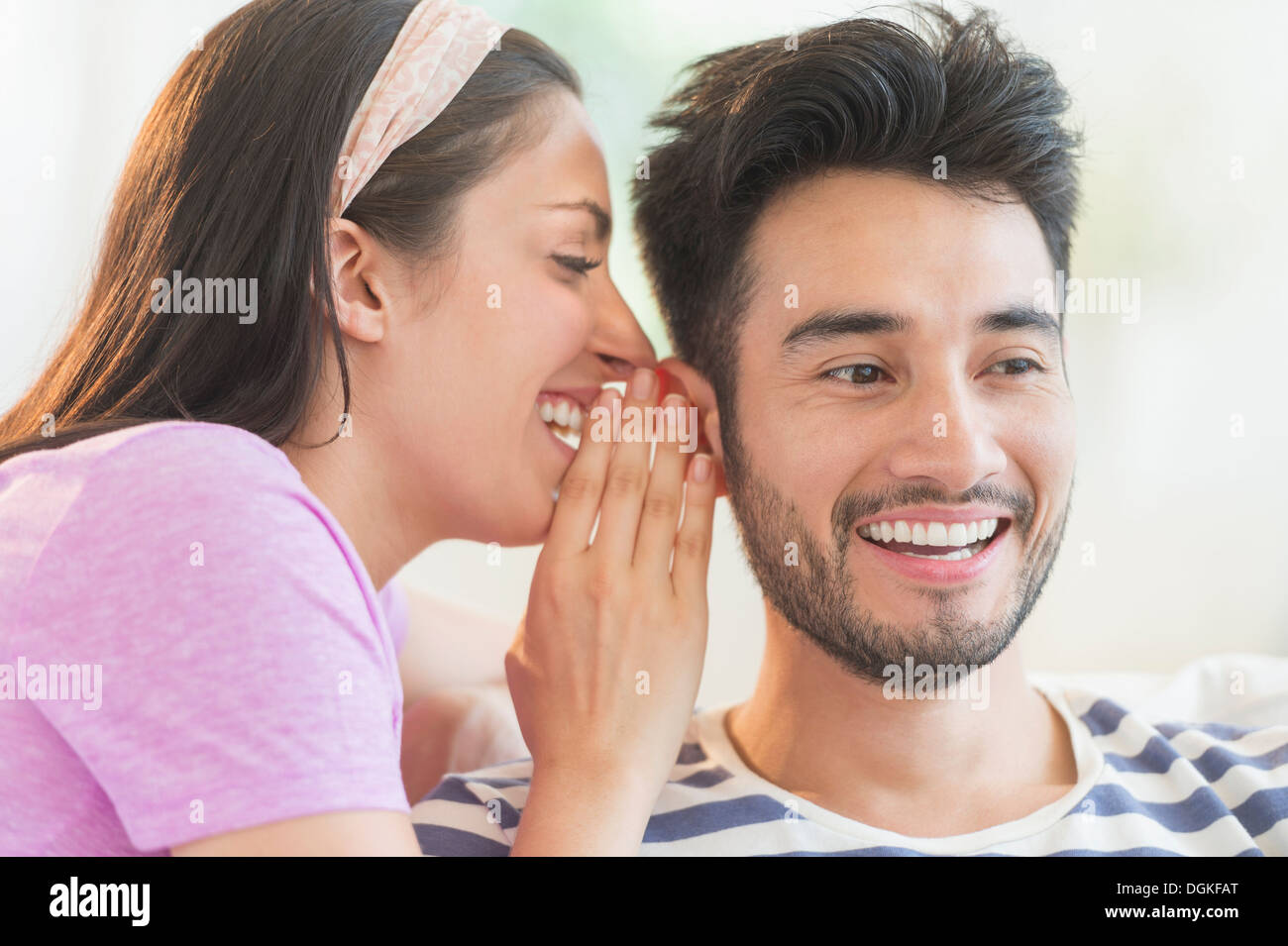 Woman whispering to man's ear Stock Photo