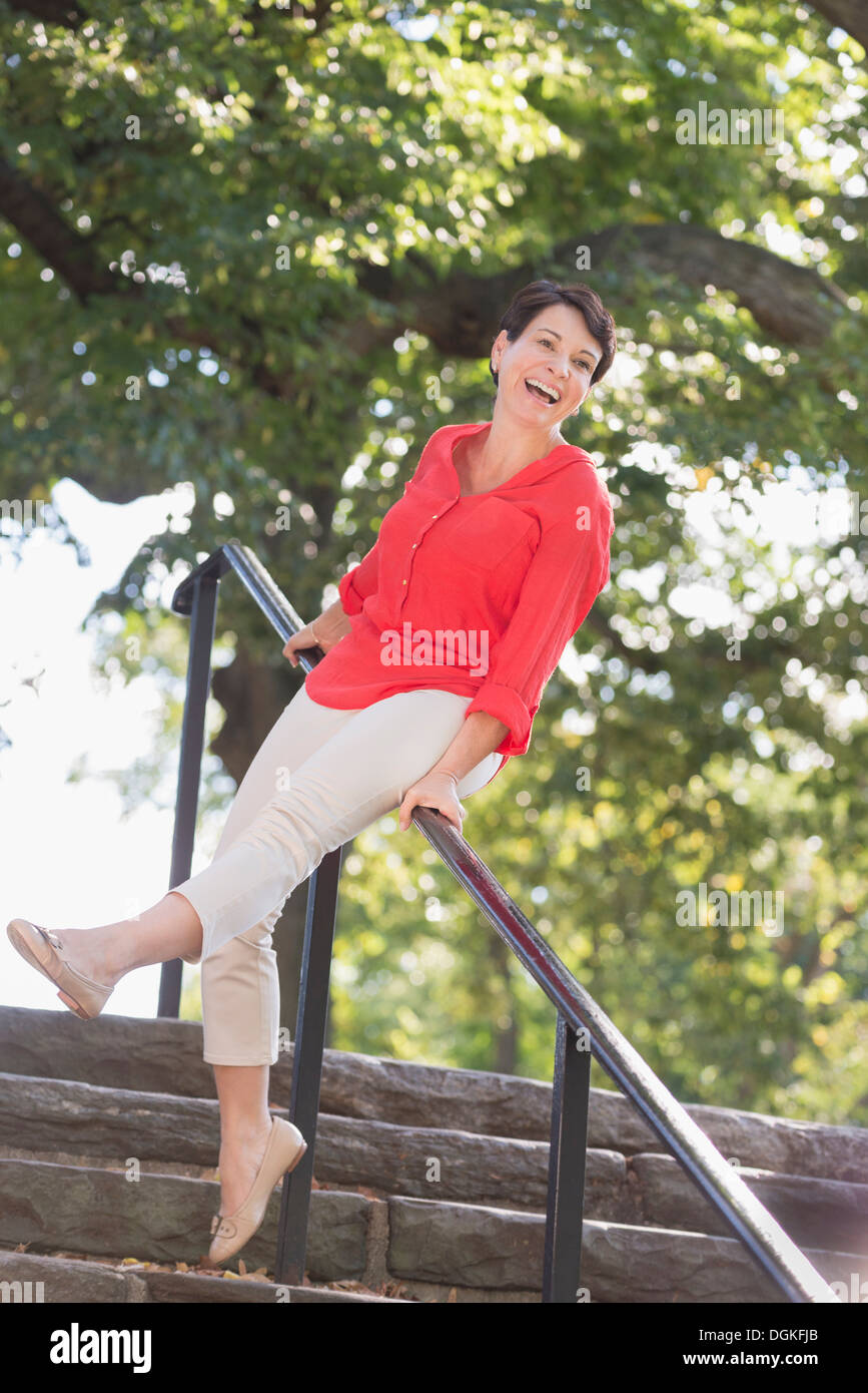 Mature woman sliding down railing in park Stock Photo Alamy