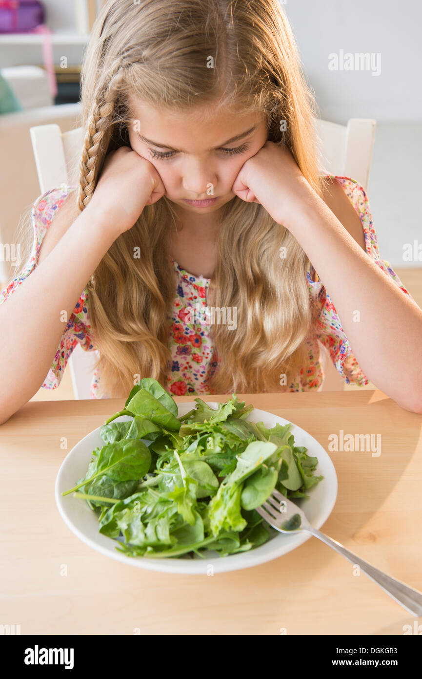 View of unhappy girl (8-9) with salad Stock Photo